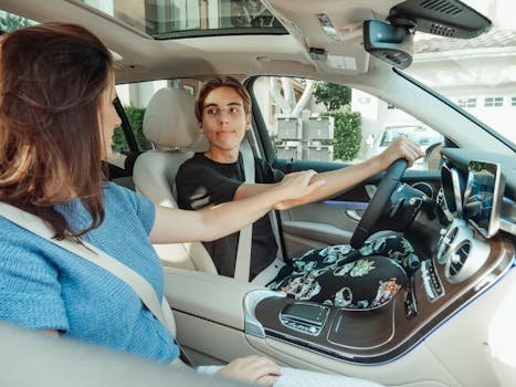Enquiries 12 A mother supports her teenage son as he learns to drive in a car